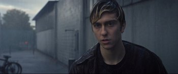 Movie still from “Death Note” (2017), directed by Adam Wingard – A young man in a black jacket is looking at the camera while standing in a dark alley; Close Up shot, Over the shoulder angle