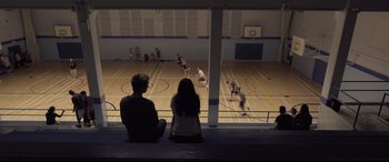 Movie still from “Death Note” (2017), directed by Adam Wingard – Two people sitting on a bench watching a basketball game; Extreme Wide shot, High angle
