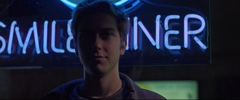 Movie still from “Death Note” (2017), directed by Adam Wingard – A young man in front of a neon sign; Close Up shot, Low angle