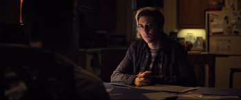 Movie still from “Death Note” (2017), directed by Adam Wingard – A man sitting at a table in a dark room; Medium shot, Over the shoulder angle