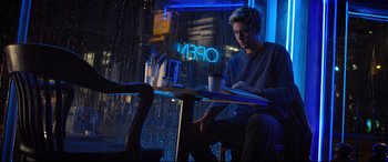 Movie still from “Death Note” (2017), directed by Adam Wingard – A man sitting at a table with a cup in front of him; Medium shot, Low angle