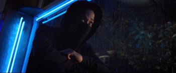 Movie still from “Death Note” (2017), directed by Adam Wingard – A man in a black hooded sweatshirt is sitting in the rain; Close Up shot, Low angle