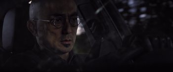 Movie still from “Death Note” (2017), directed by Adam Wingard – A man wearing glasses sitting in a car looking out the window; Close Up shot, Low angle