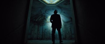 Movie still from “Death Note” (2017), directed by Adam Wingard – A man in a suit standing in a dark room; Wide shot, Low angle