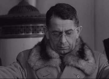 Movie still from “Closely Watched Trains” (1966), directed by Jirí Menzel – An older man wearing glasses and a fur collar; Close Up shot, Over the shoulder angle