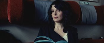 Movie still from “Clouds of Sils Maria” (2014), directed by Olivier Assayas – A woman sitting in a chair with a book in her lap; Close Up shot, High angle