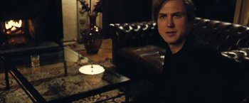 Movie still from “Clouds of Sils Maria” (2014), directed by Olivier Assayas – A man sitting in a living room next to a coffee table; Close Up shot, Over the shoulder angle