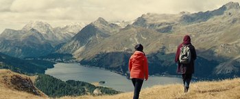 Movie still from “Clouds of Sils Maria” (2014), directed by Olivier Assayas – A woman in a red jacket standing on top of a hill; Extreme Wide shot, High angle