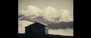 Movie still from “Clouds of Sils Maria” (2014), directed by Olivier Assayas – An old stone building with a cross on the top of it; Extreme Wide shot, Low angle