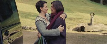 Movie still from “Clouds of Sils Maria” (2014), directed by Olivier Assayas – Two women embracing each other in a grassy area; Medium shot, Low angle