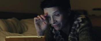 Movie still from “Clouds of Sils Maria” (2014), directed by Olivier Assayas – A woman is looking at the camera while holding her hand to her face; Close Up shot, High angle