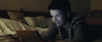 Movie still from “Clouds of Sils Maria” (2014), directed by Olivier Assayas – A woman laying on a bed looking at a tablet computer; Close Up shot, Low angle