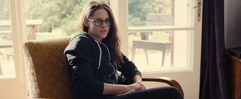 Movie still from “Clouds of Sils Maria” (2014), directed by Olivier Assayas – A woman sitting in a chair wearing glasses and a hoodie; Medium shot, Over the shoulder angle