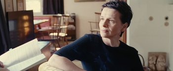 Movie still from “Clouds of Sils Maria” (2014), directed by Olivier Assayas – A woman sitting on a chair in front of a window; Close Up shot, Over the shoulder angle