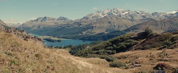 Movie still from “Clouds of Sils Maria” (2014), directed by Olivier Assayas – A view of a mountain range with a lake in the background; Extreme Wide shot, High angle