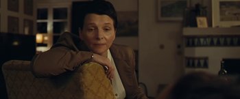 Movie still from “Clouds of Sils Maria” (2014), directed by Olivier Assayas – An older woman sitting in a chair with her arms around a bag; Close Up shot, High angle