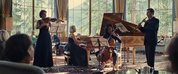 Movie still from “Clouds of Sils Maria” (2014), directed by Olivier Assayas – A group of people sitting at a table playing musical instruments; Wide shot, Low angle