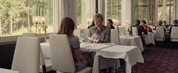Movie still from “Clouds of Sils Maria” (2014), directed by Olivier Assayas – A man and woman sitting at a table in a restaurant; Medium shot, Over the shoulder angle