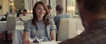 Movie still from “Clouds of Sils Maria” (2014), directed by Olivier Assayas – A woman sitting at a table with a glass of wine in front of her; Medium shot, Over the shoulder angle
