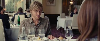 Movie still from “Clouds of Sils Maria” (2014), directed by Olivier Assayas – A man sitting at a table in front of a plate of food; Medium shot, Over the shoulder angle