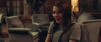 Movie still from “Clouds of Sils Maria” (2014), directed by Olivier Assayas – A young woman sitting in a chair smiling; Medium shot, Over the shoulder angle