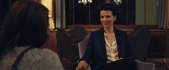 Movie still from “Clouds of Sils Maria” (2014), directed by Olivier Assayas – A woman sitting in a chair in front of a window; Medium shot, Over the shoulder angle