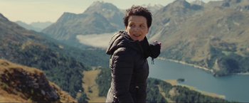 Movie still from “Clouds of Sils Maria” (2014), directed by Olivier Assayas – A woman standing on top of a hill with a mountain in the background; Close Up shot, Low angle