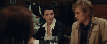 Movie still from “Clouds of Sils Maria” (2014), directed by Olivier Assayas – A woman sitting at a table with a glass of wine; Medium shot, Over the shoulder angle
