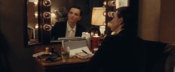 Movie still from “Clouds of Sils Maria” (2014), directed by Olivier Assayas – A man sitting in front of a mirror in front of a woman; Medium shot, Over the shoulder angle