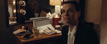 Movie still from “Clouds of Sils Maria” (2014), directed by Olivier Assayas – A man sitting at a table with a glass of water; Close Up shot, Over the shoulder angle