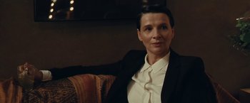 Movie still from “Clouds of Sils Maria” (2014), directed by Olivier Assayas – A woman sitting on a couch wearing a suit; Close Up shot, Over the shoulder angle