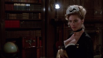 Movie still from “Clue” (1985), directed by Jonathan Lynn – A woman in a black dress holding a glass of wine; Close Up shot, Over the shoulder angle