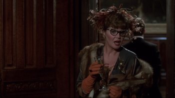 Movie still from “Clue” (1985), directed by Jonathan Lynn – A woman in a fur coat holding a glass of wine; Close Up shot, Over the shoulder angle