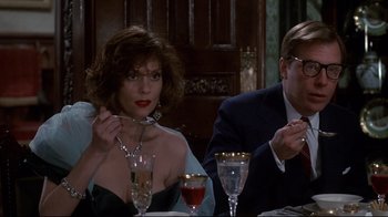 Movie still from “Clue” (1985), directed by Jonathan Lynn – A man and a woman sitting at a dinner table; Medium shot, Low angle