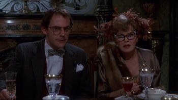 Movie still from “Clue” (1985), directed by Jonathan Lynn – A man and a woman sitting at a dinner table; Close Up shot, Low angle