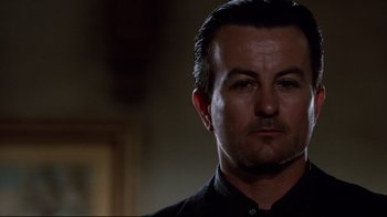 Movie still from “Clue” (1985), directed by Jonathan Lynn – A person wearing a black shirt; Close Up shot, Low angle