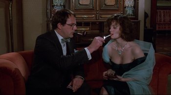 Movie still from “Clue” (1985), directed by Jonathan Lynn – A man and a woman sitting on a couch; Medium shot, Over the shoulder angle