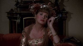 Movie still from “Clue” (1985), directed by Jonathan Lynn – An older woman in a dress and a hat holding a cell phone; Close Up shot, Over the shoulder angle