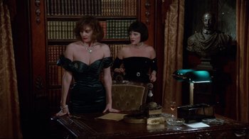 Movie still from “Clue” (1985), directed by Jonathan Lynn – Two women are standing at a desk in front of a book case; Medium shot, Low angle