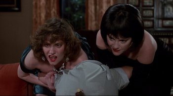Movie still from “Clue” (1985), directed by Jonathan Lynn – A group of people that are sitting on a couch; Medium shot, Over the shoulder angle