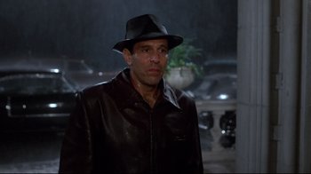 Movie still from “Clue” (1985), directed by Jonathan Lynn – A man wearing a leather jacket and a hat; Medium shot, Over the shoulder angle