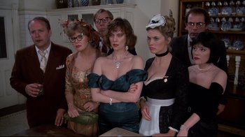 Movie still from “Clue” (1985), directed by Jonathan Lynn – A group of people standing next to each other in a room; Medium shot, High angle
