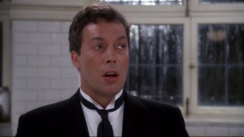 Movie still from “Clue” (1985), directed by Jonathan Lynn – A person wearing a suit and a tie; Close Up shot, Over the shoulder angle