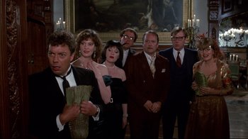 Movie still from “Clue” (1985), directed by Jonathan Lynn – A group of people standing next to each other in front of a painting; Medium shot, High angle