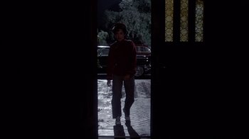 Movie still from “Clue” (1985), directed by Jonathan Lynn – A man standing in a doorway in the dark; Wide shot, Low angle
