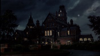 Movie still from “Clue” (1985), directed by Jonathan Lynn – A large building that is lit up at night; Extreme Wide shot, Low angle