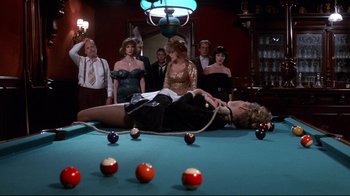 Movie still from “Clue” (1985), directed by Jonathan Lynn – A group of people standing around a pool table; Wide shot, High angle