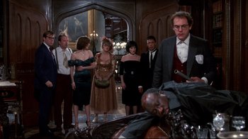 Movie still from “Clue” (1985), directed by Jonathan Lynn – A group of people standing in a room; Wide shot, Low angle