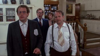 Movie still from “Clue” (1985), directed by Jonathan Lynn – A group of people standing in a living room; Medium shot, Over the shoulder angle