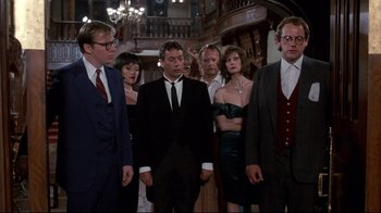 Movie still from “Clue” (1985), directed by Jonathan Lynn – A group of people standing in a room together; Medium shot, Low angle